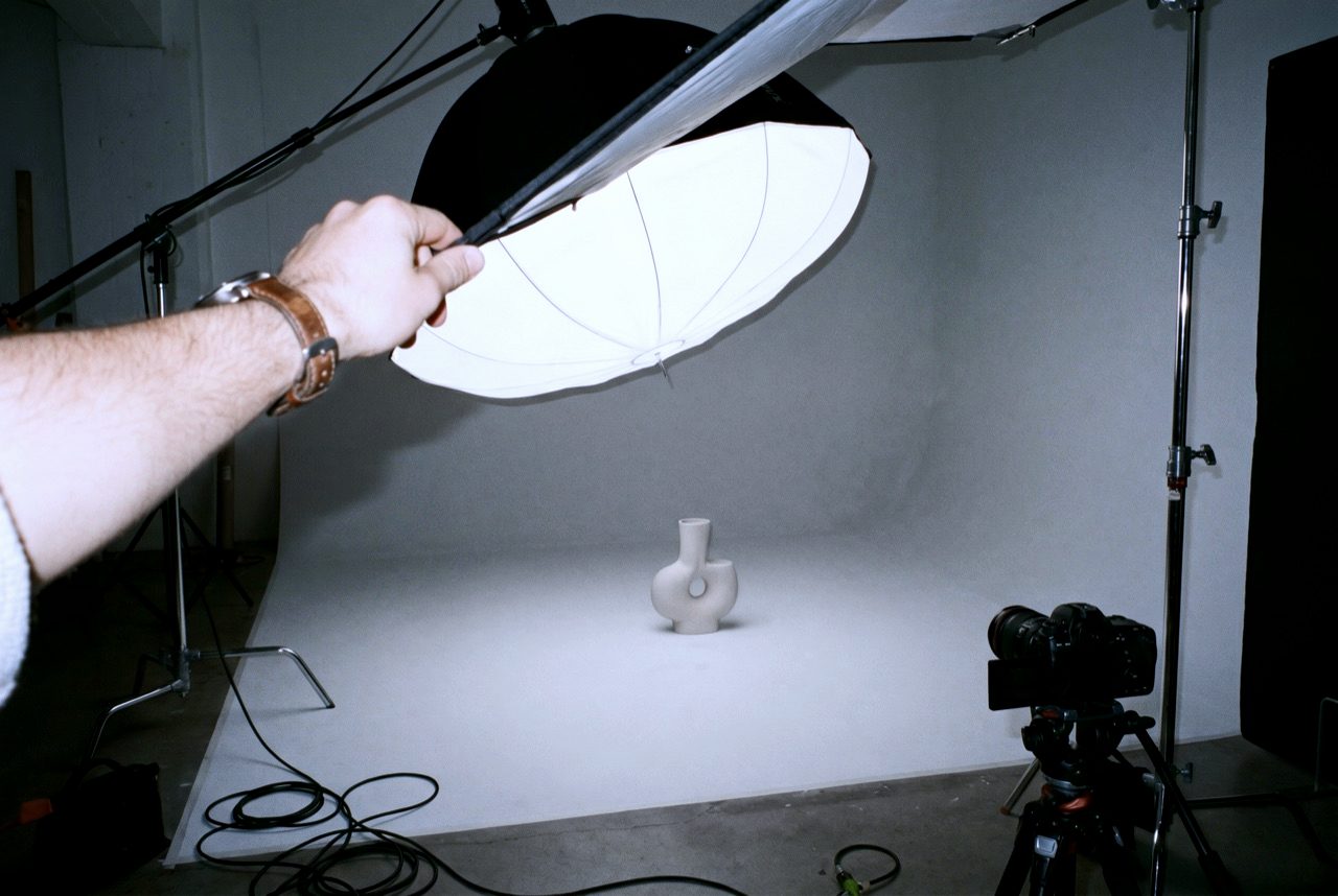 Studio-Setup: Eine Hand justiert das Licht über dem Hauptmotiv