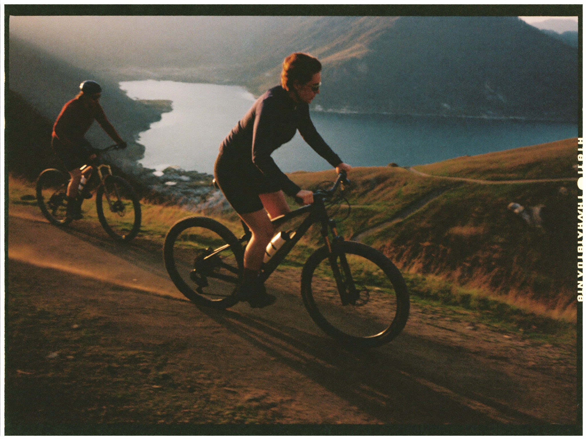 Mountainbiker auf einem Schotterweg hoch über dem Gardasee in der Abendsonne